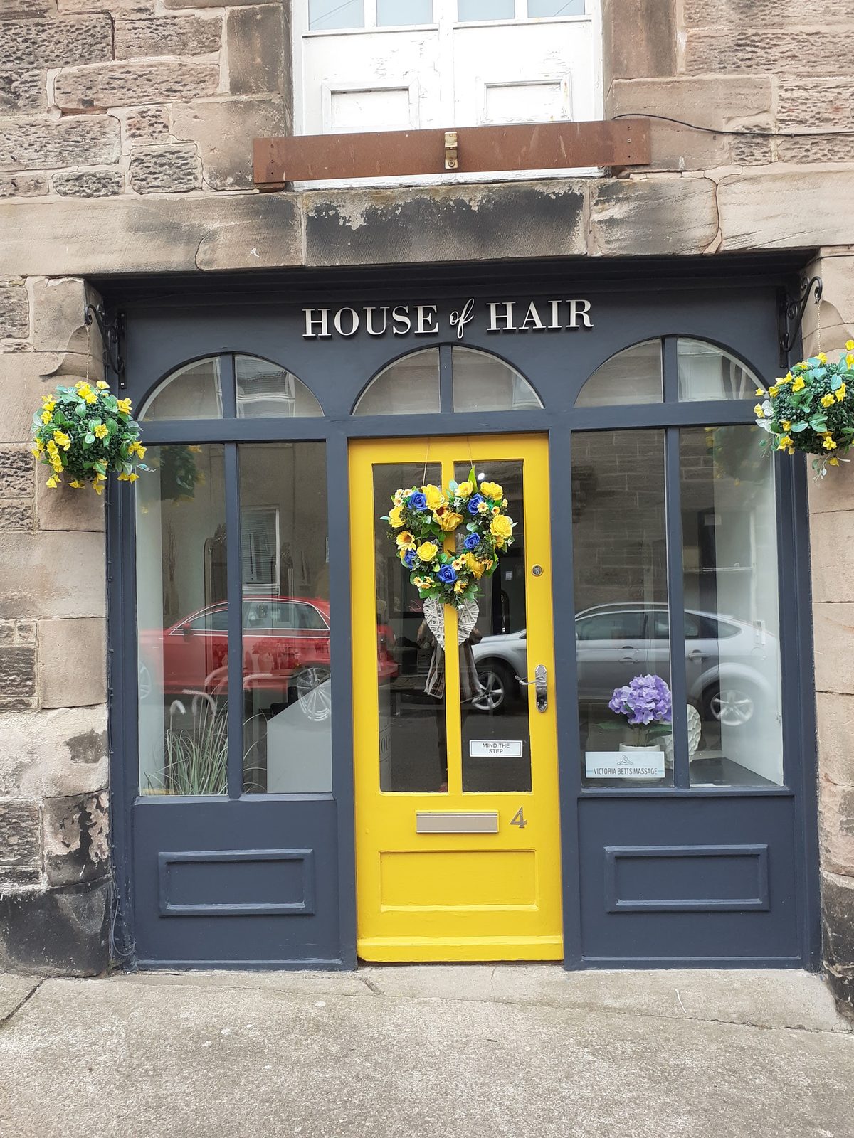 The House of Hair shopfront at 4 Tweed Street with its navy frontage and yellow door